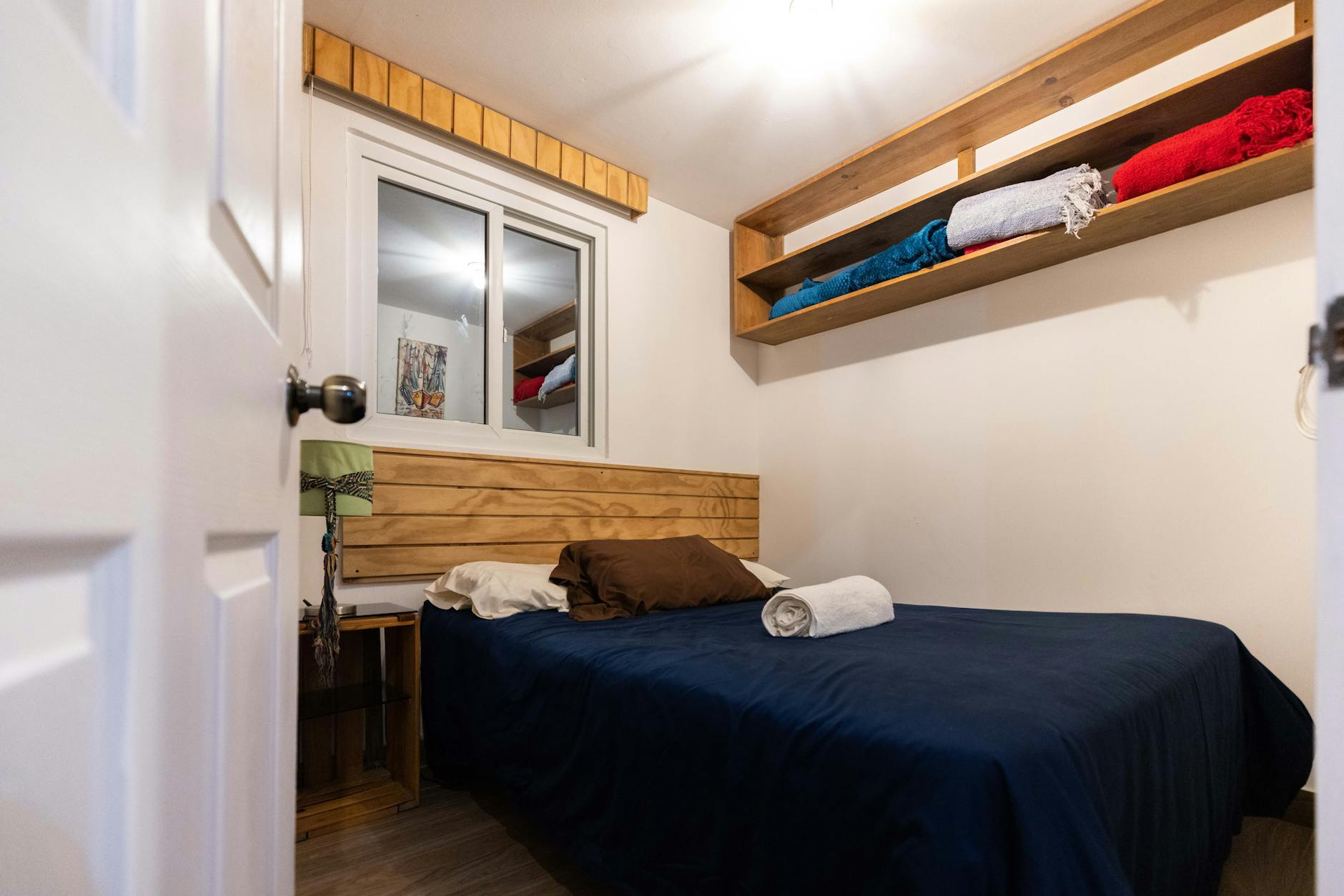 Przytulny pokój młodzieżowy z łóżkiem, drewnianymi półkami i oknem