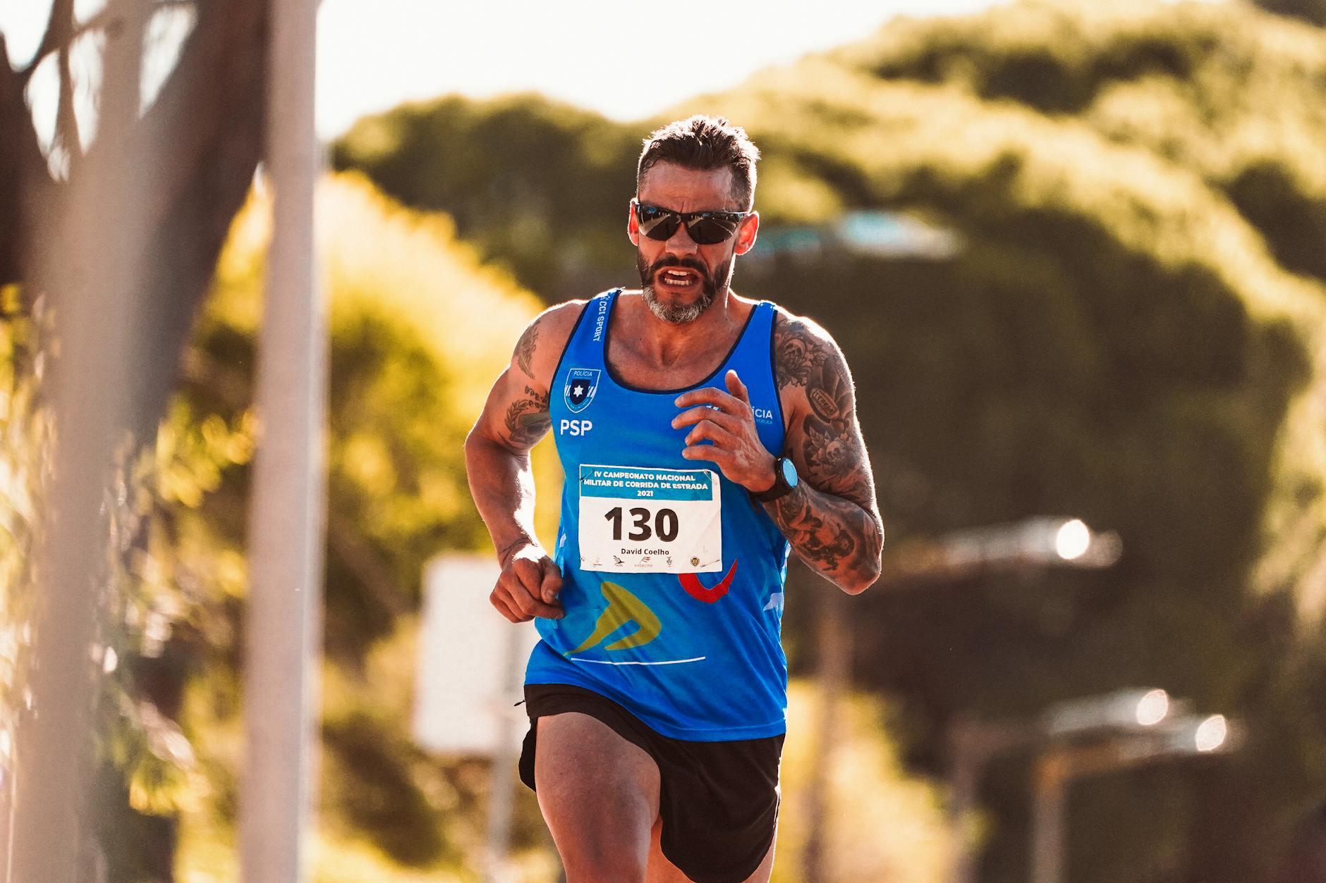 Jak poprawić ekonomię biegu: technika, kadencja i siła, które robią różnicę Biegacz z tatuażami w okularach słonecznych podczas maratonu na słońcu