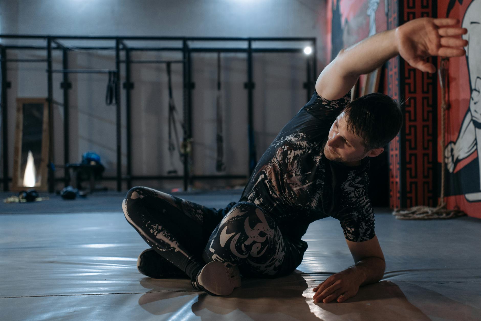 Mężczyzna rozciąga się w sali MMA przed treningiem siłowym