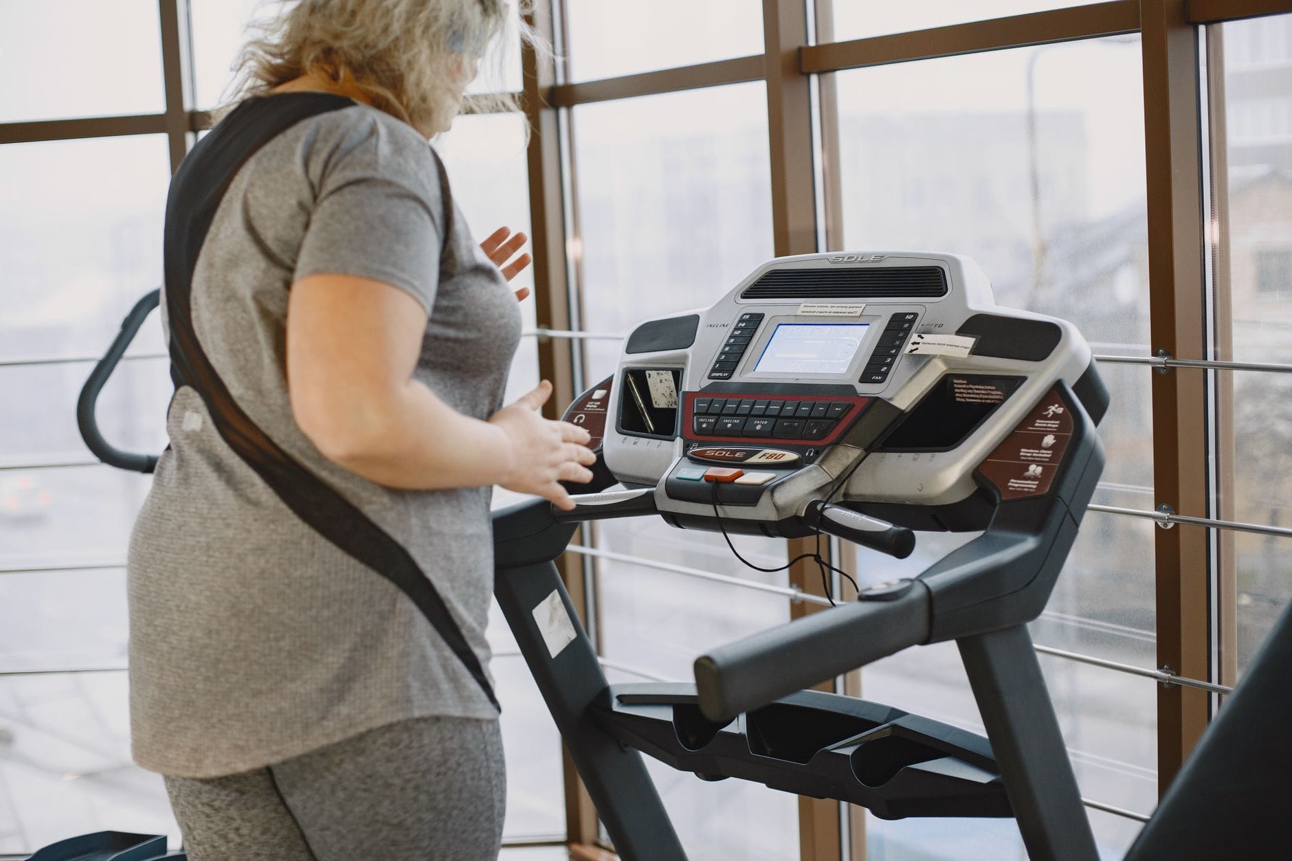 Bieżnia w domu: jak trenować cardio, żeby nie przeciążyć łydek Kobieta ćwicząca na bieżni w siłowni podczas treningu cardio