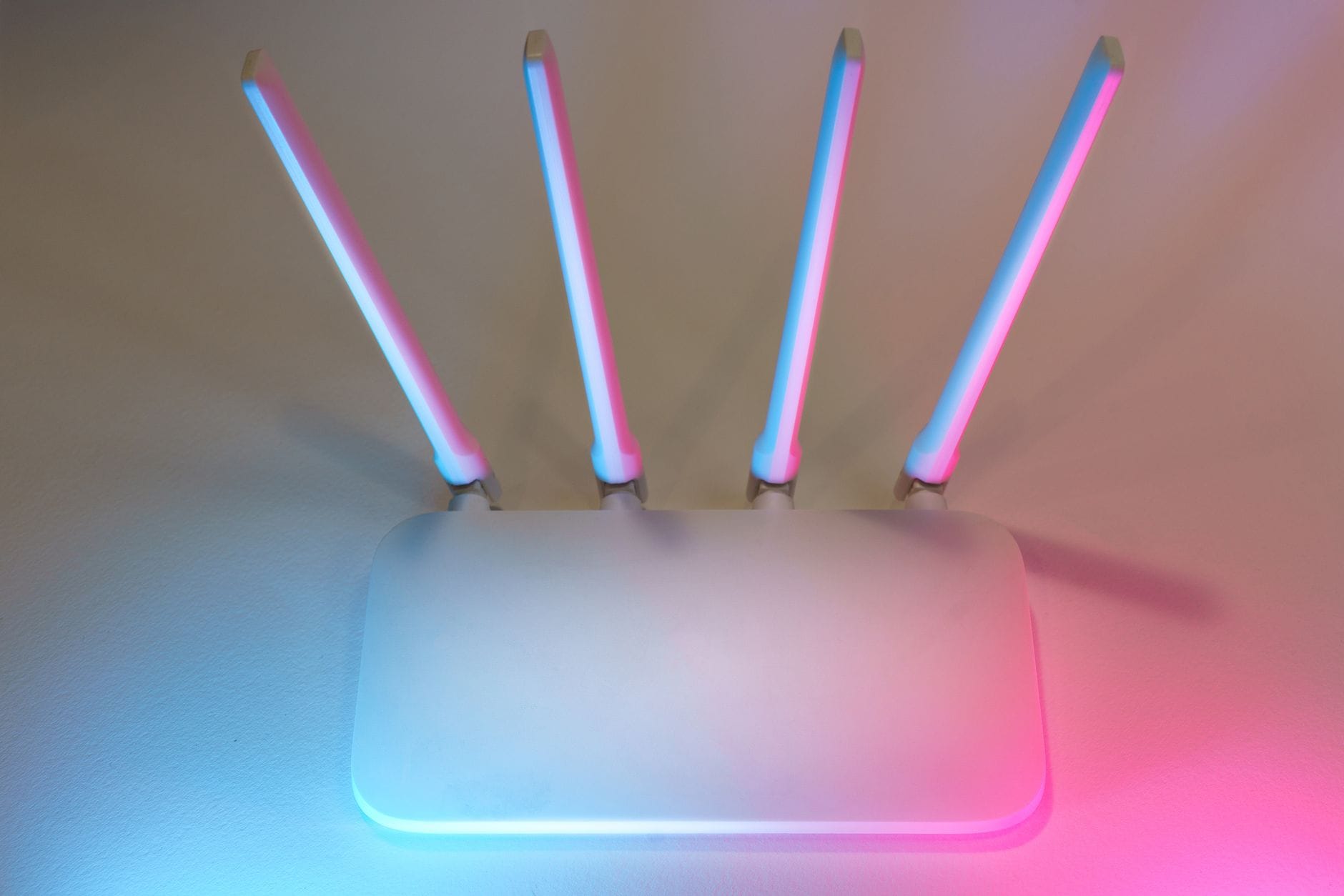 Jak wybrać najlepszy router LTE lub 5G do internetu domowego i na wyjazdy Nowoczesny biały router z czterema antenami podświetlony na niebiesko i różowo