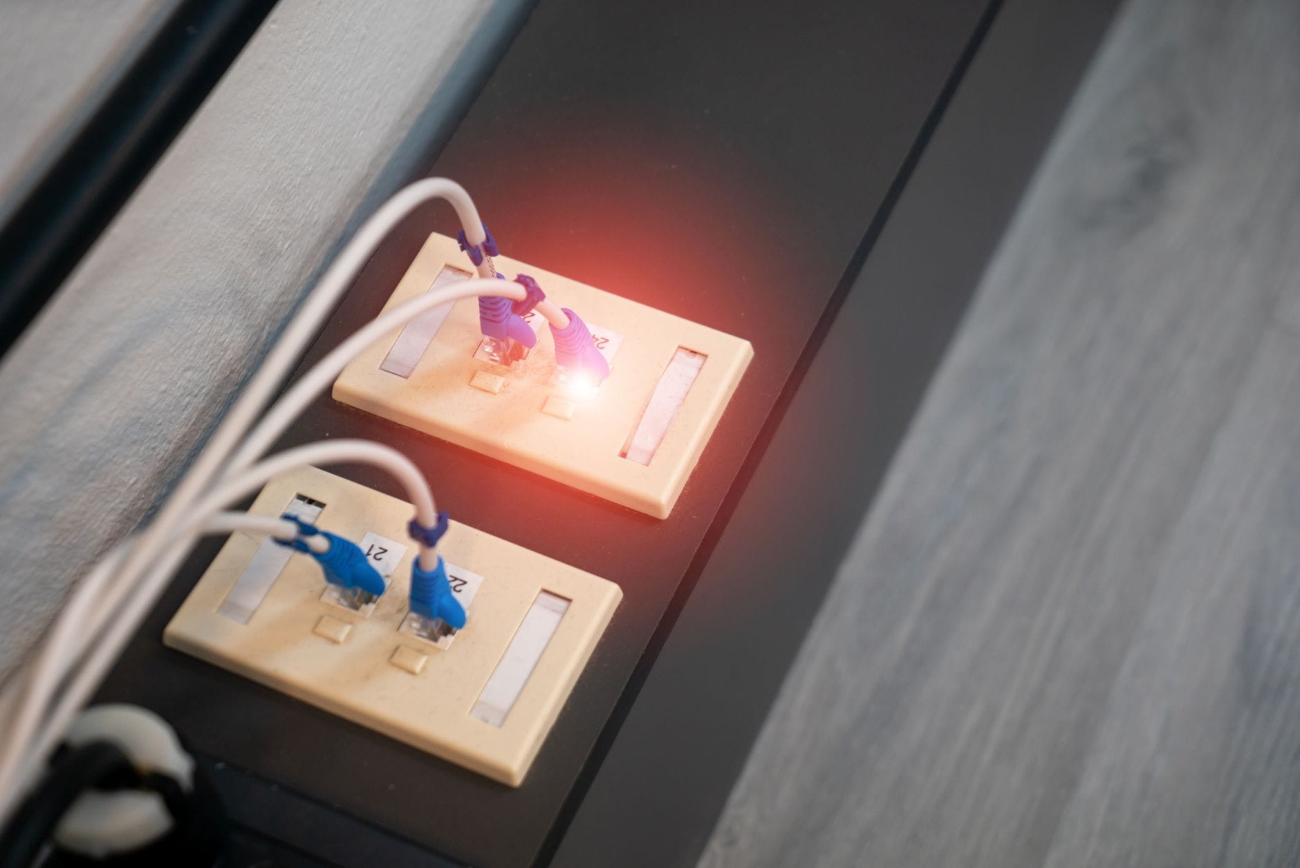 Zbliżenie portów Ethernet z podłączonymi kablami i świecącymi diodami