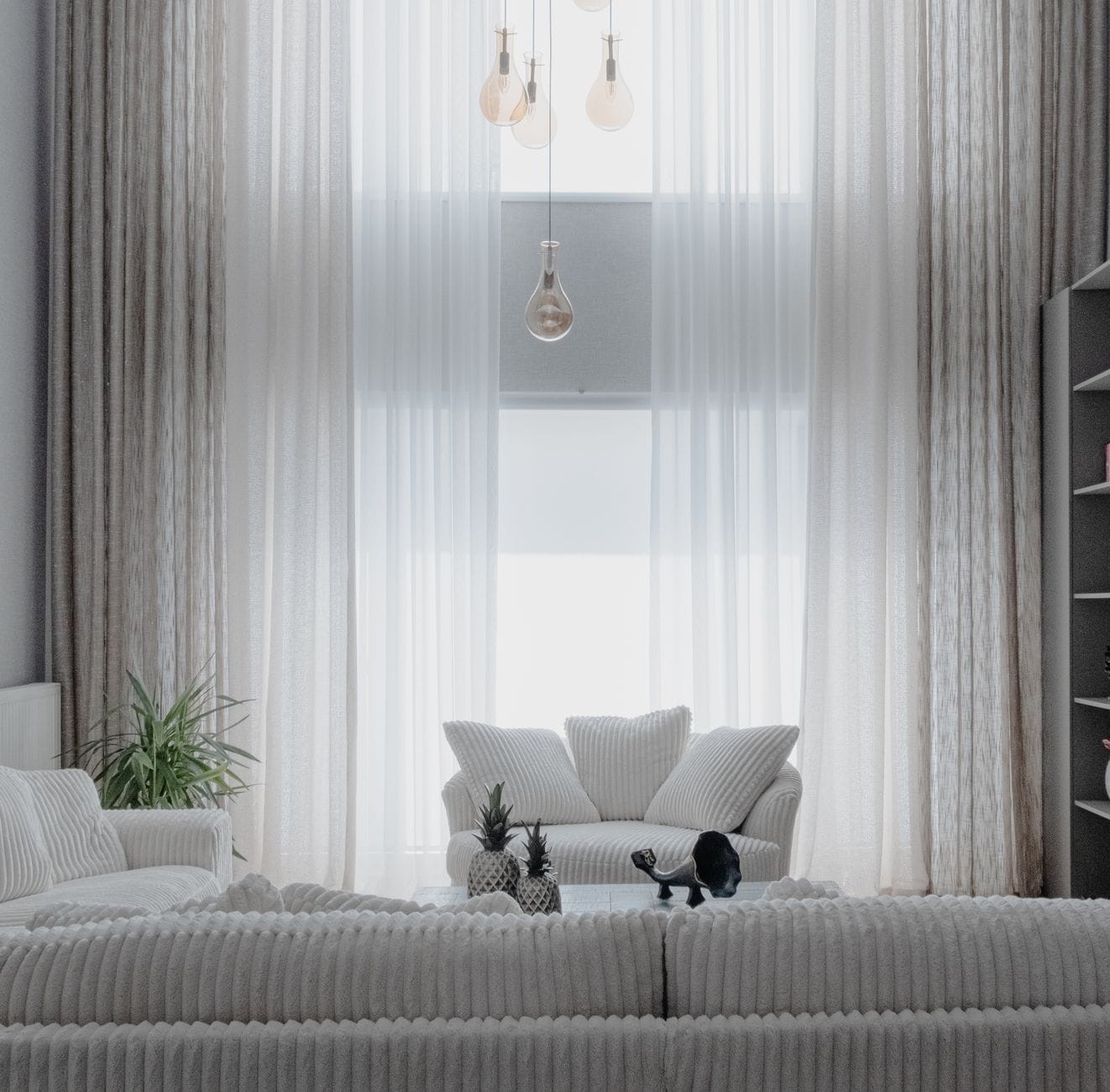 Nowoczesny, minimalistyczny salon z jasnymi sofami i zasłonami