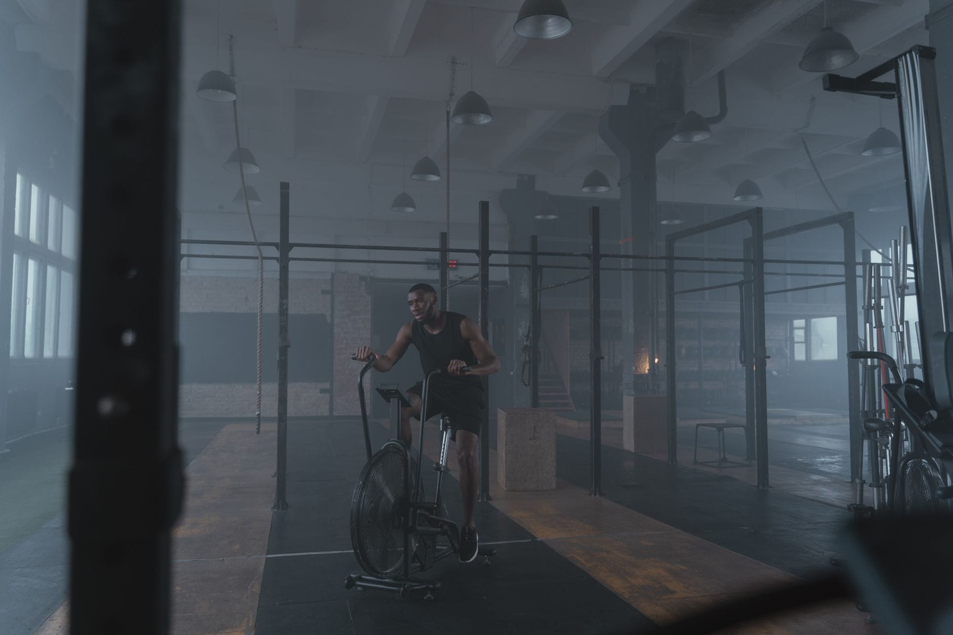 Skoncentrowany sportowiec trenuje na rowerze stacjonarnym w siłowni industrialne