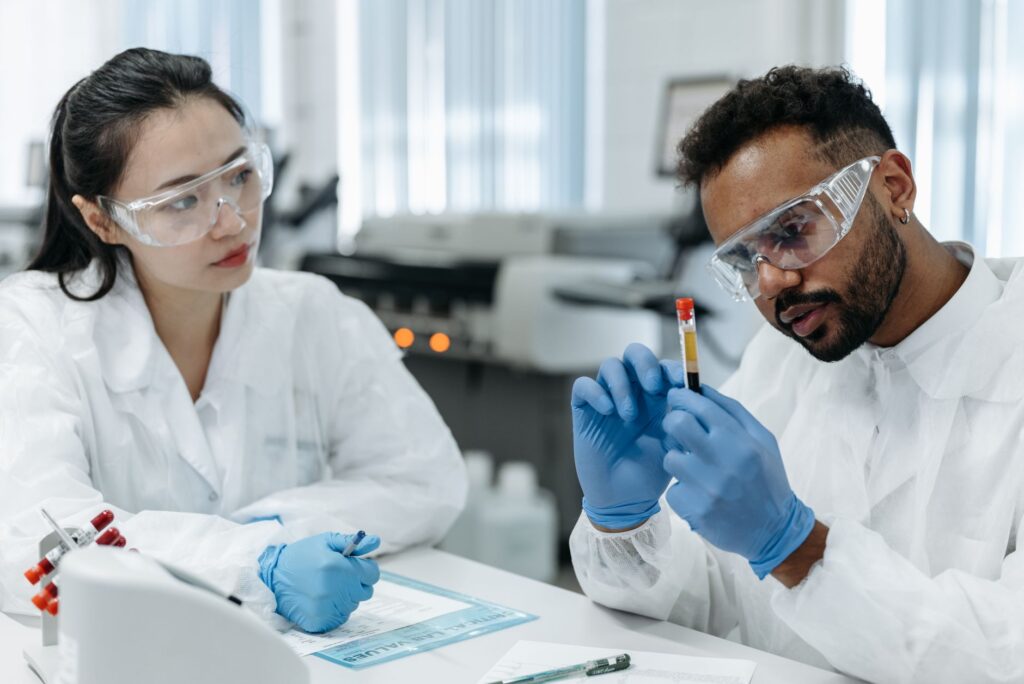 Dwóch naukowców w odzieży ochronnej analizuje próbki krwi w laboratorium